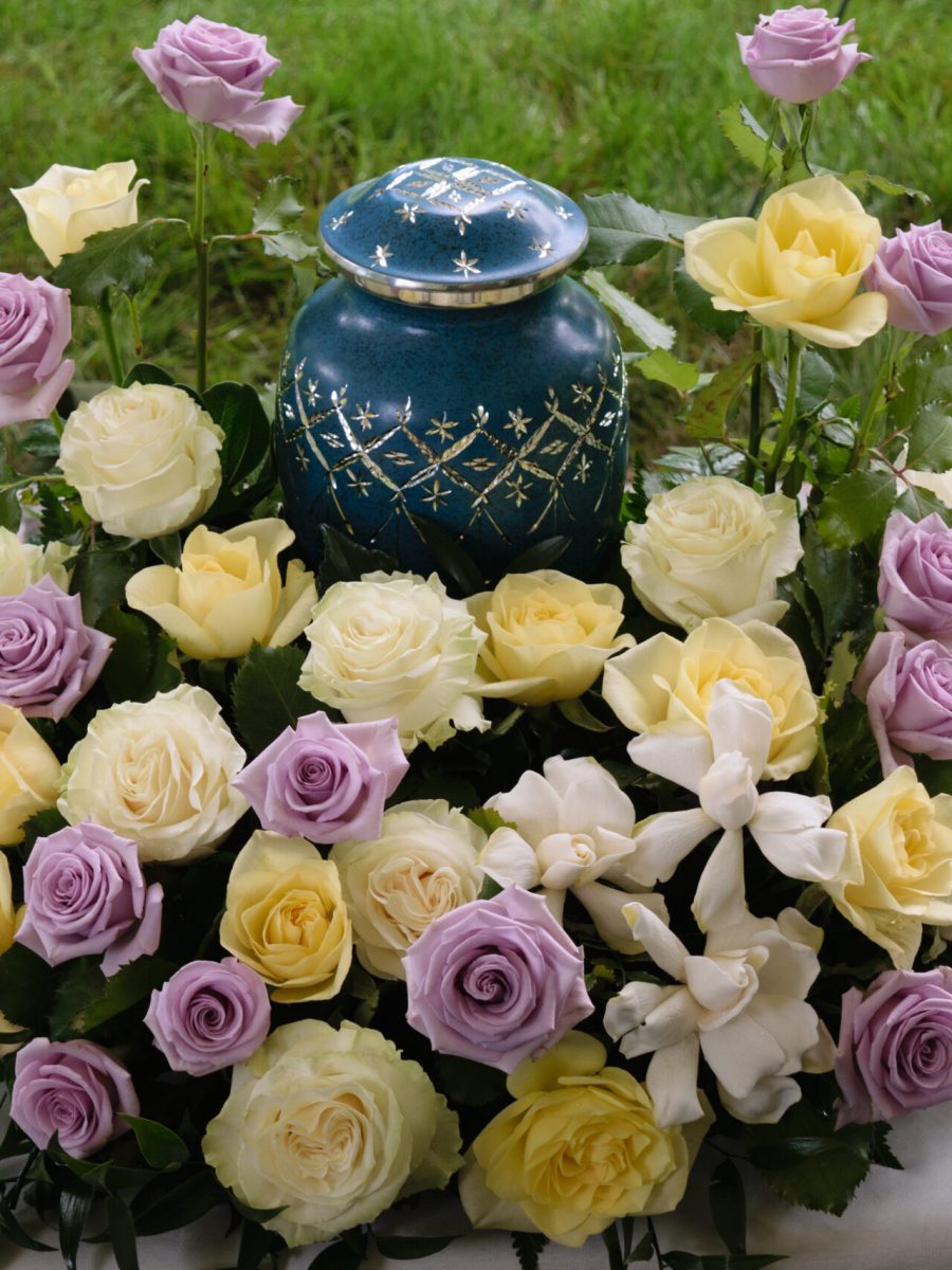 funeral and mourning concept - flowers surrounding urn