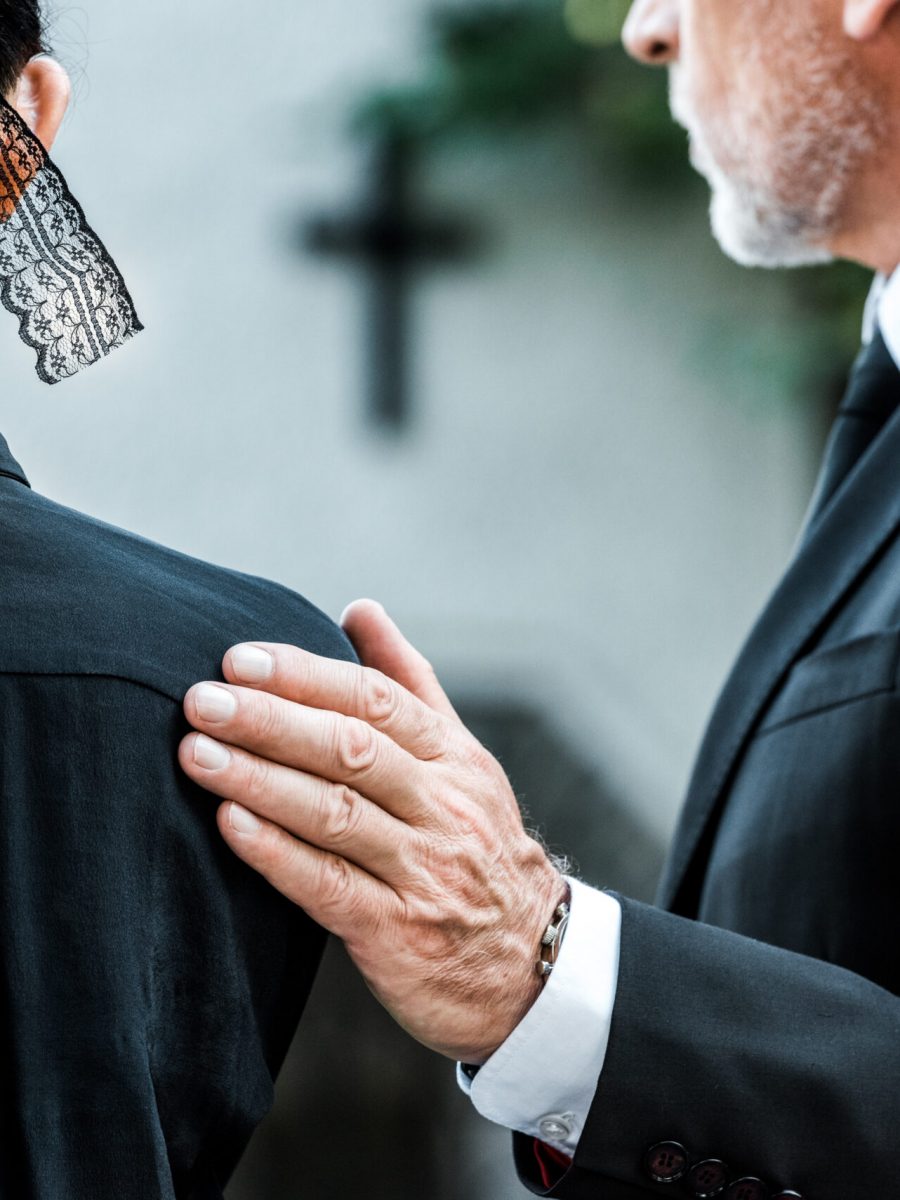 cropped view of man touching woman on funeral